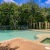 a swimming pool with trees and a building in the background